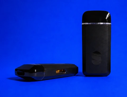 Two black Briq devices on blue, one lying flat behind the other